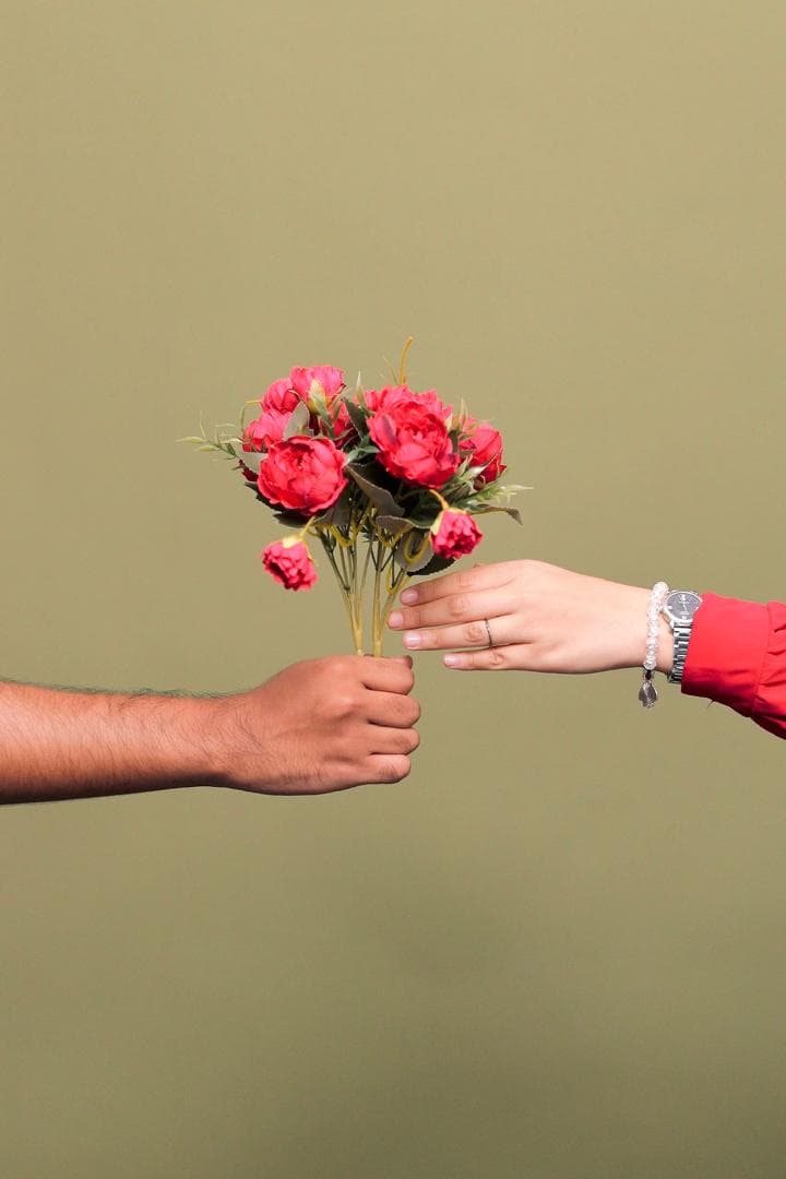 Bouquet of red roses passed from the groom's hand to the bride's